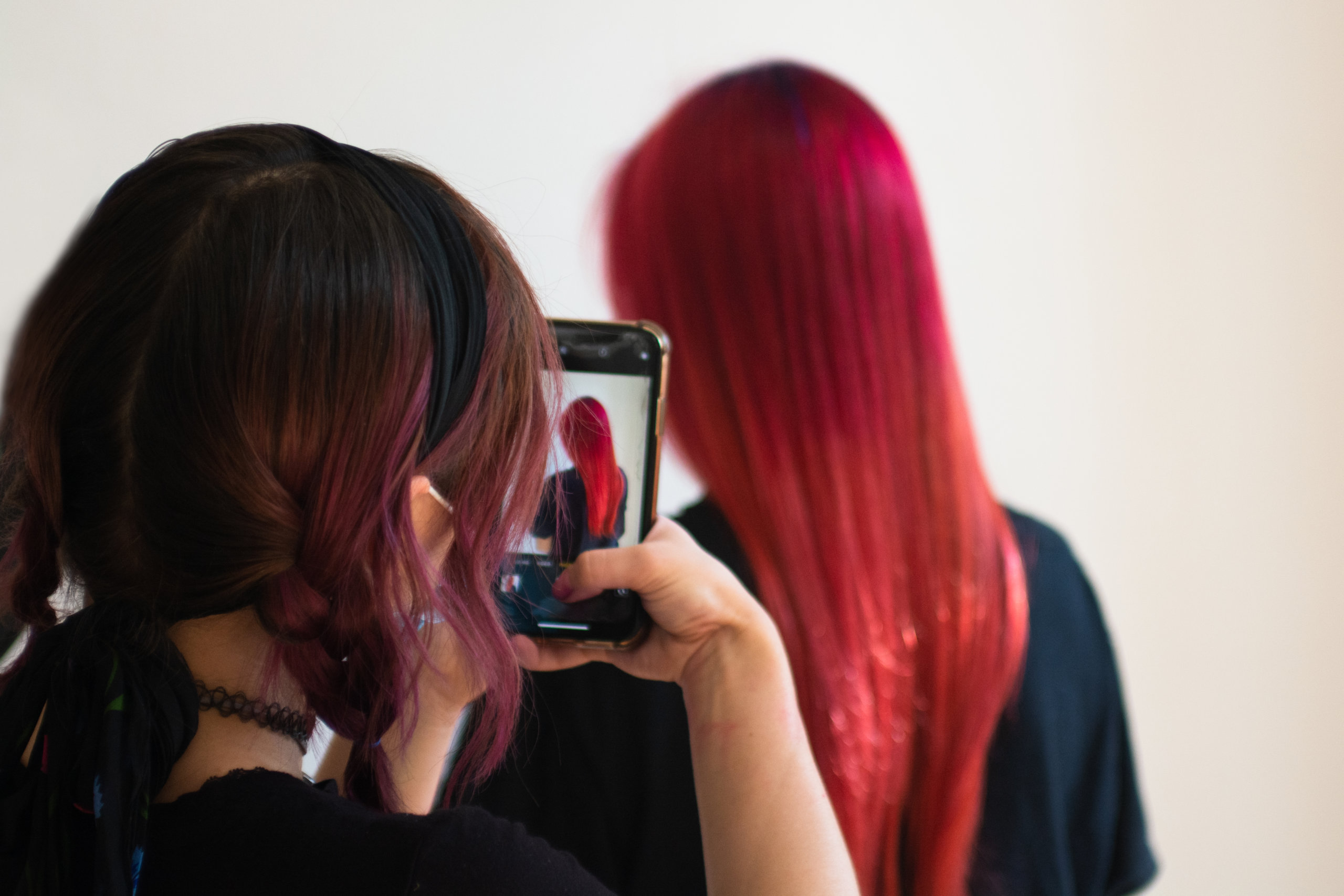 Hair stylist Natalie taking a photo of her vivid red haired client.